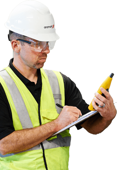 facility worker wearing a hard hat and writing on a clipboard