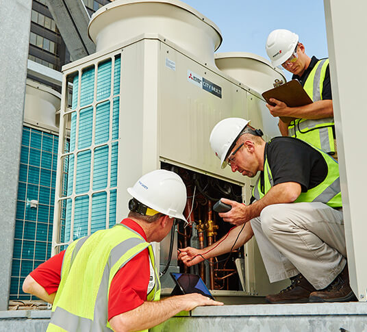 group of facility workers fixing equipment on a rooftop